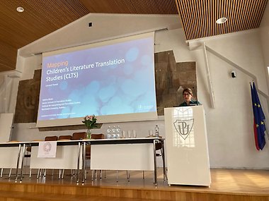 Valérie Alfvén behind a lectern, with a big projector screen in the background.