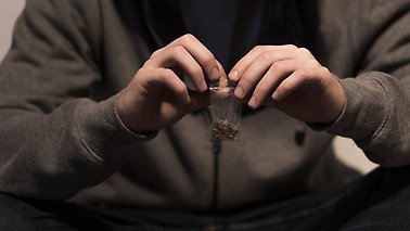 En man öppnar en påse med marijuana.