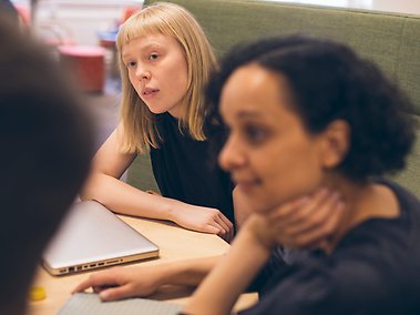 Studenter sitter runt bord och samtalar