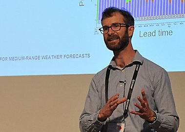 Linus står och pratar och gestikulerar framför en storbildsskärm.