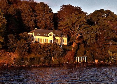 Stor villa sedd från avstånd från en sjö.
