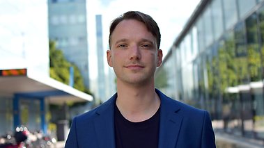 Zeth Isaksson står utomhus med campusbyggnaden i bakgrunden.