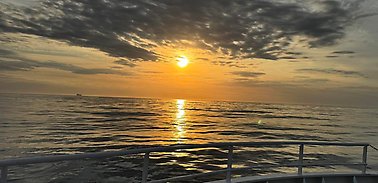 Sunset over the Atlantic Ocean. Ship railing in the foreground.