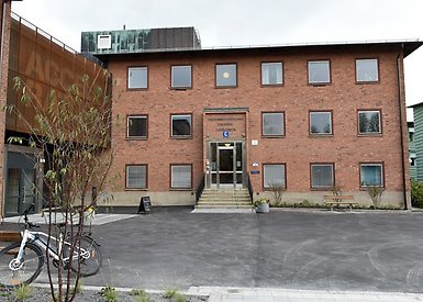 Trevåningshus i brunt tegel. Till vänster ingången till konsthallen Accelerator.