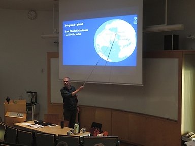 Henrik Swärd står framför en stor filmduk och föreläser, nordenskiöldsalen, stockholm universitet