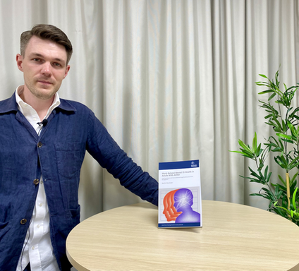 Martin Oscarsson standing by a table featuring his thesis.