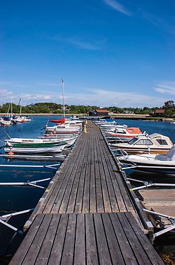 Segel- och motorbåtar längs båda sidor av bryggan vid Kullaviks hamn.
