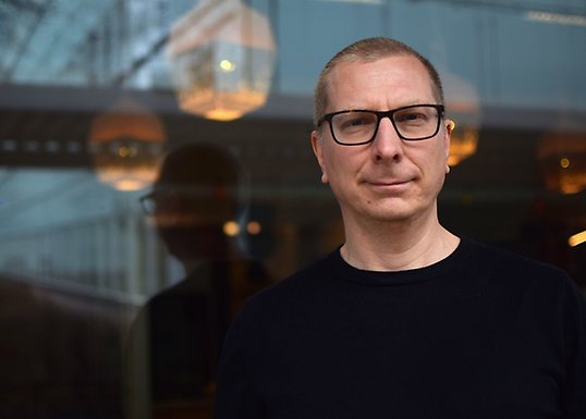 Martin Hällsten står framför en glasfasad.