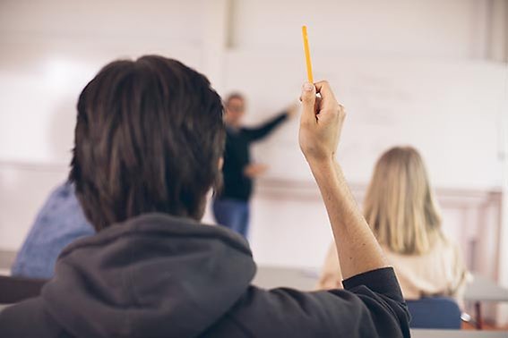 studenter räcker upp handen i lärosal
