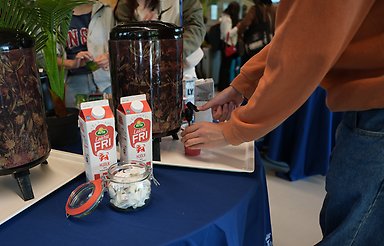 Hands filling a paper cup with coffee.