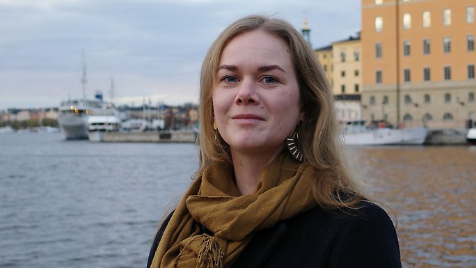 Signe Svallfors standing by the sea, Stockholm City Hall in the background.