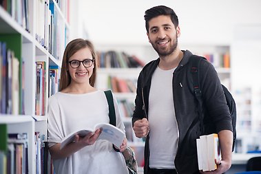 Två studenter i biblioteksmiljö.