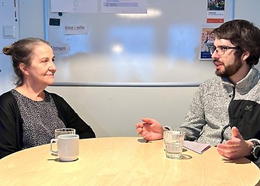 Eva Nobel och Roger Cattaneo sitter vid ett bord och samtalar.