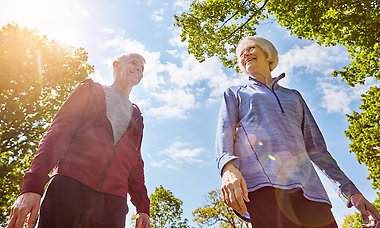 Senior couple in nature, sun shining through the trees.