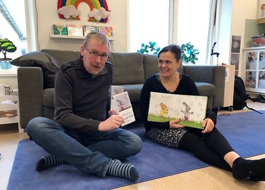 Mathias och Barbara sitter på golvet och visar fram flerspråkigt material
