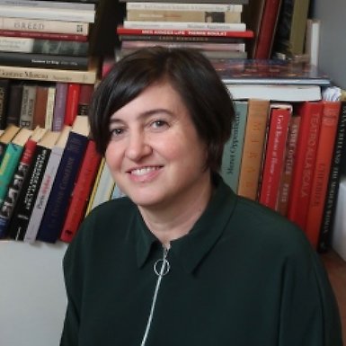 Andrea Kollnitz sitter framför en bokhylla. Hon ler.