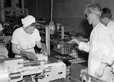 Svartvitt foto med två personer i glassfabrik 1954.