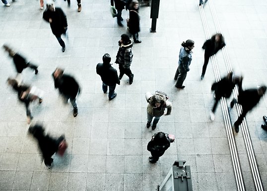 People walking in different directions on a street seen from above.