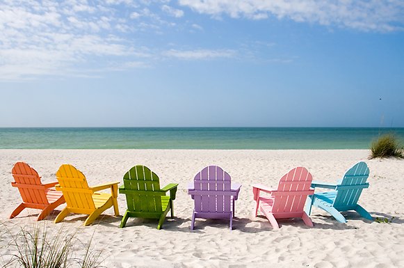 Sunchairs in different colours on a beach, facing the ocean.