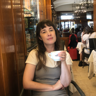 Adéle Askelöf sitter på restaurang i Rom med en kaffekopp i handen.