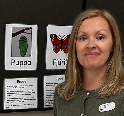 Anna Tisljarec står framför en vägg med skolplancher.