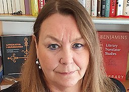 Yvonne Lindqvist tittar upp mot kameran, med bokhylla i bakgrunden.