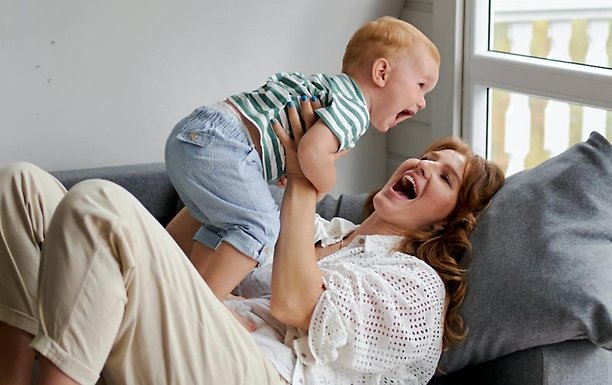 Mamma och baby kommunicerar i en soffa.