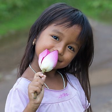 Smiling girl smelling a lotus flower.