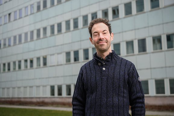 Kieron Barclay står utomhus med campusbyggnaden i bakgrunden.