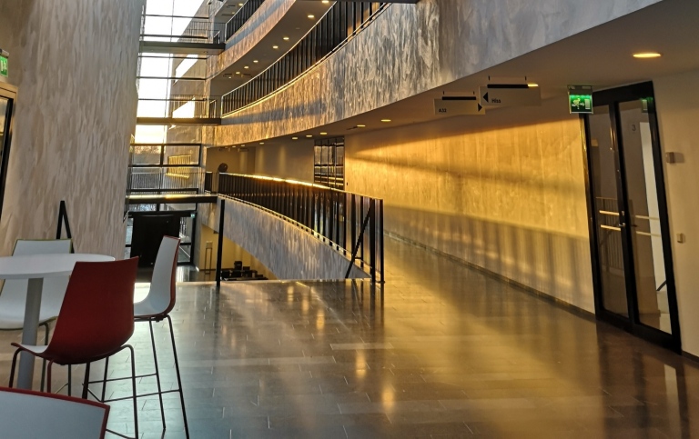 A hallway lit with sunset colors, with a table and chairs to the left and a door to the right.